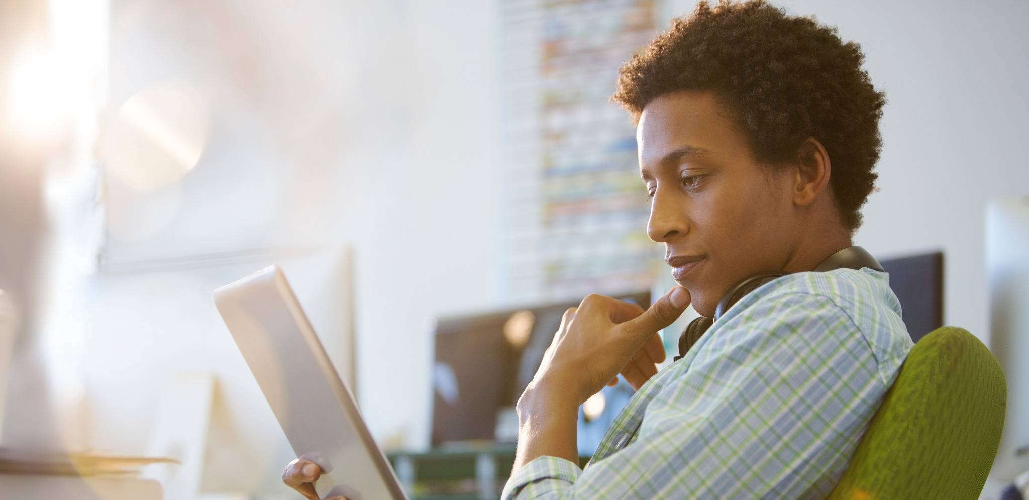 Ein Mann schaut nachdenklich auf sein Tablet und hält sich das Kinn